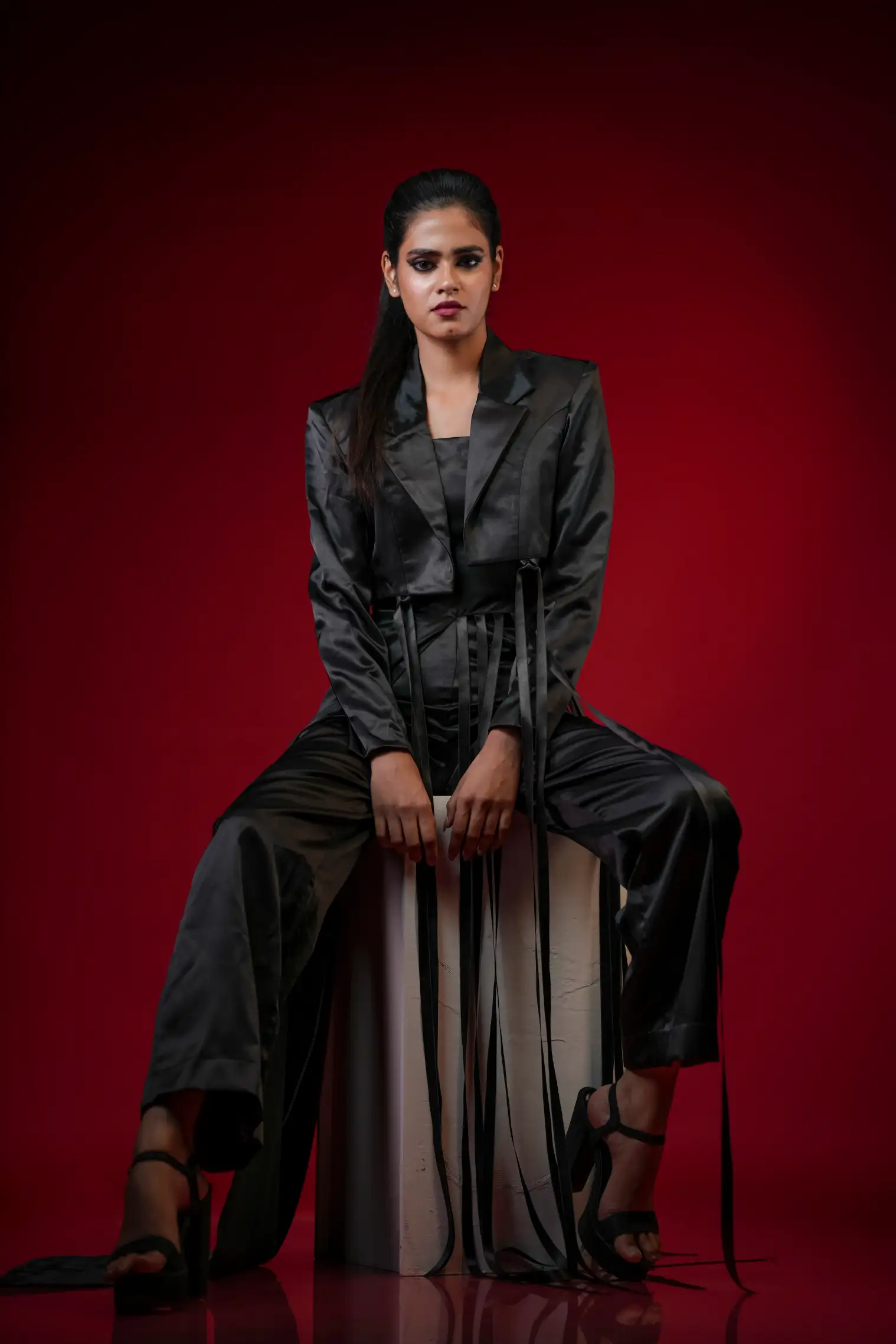 Fashion photograph from Photowant’s previous work, featuring a seated model against a red studio background